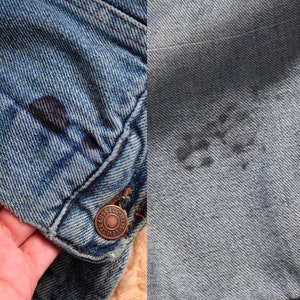 Puede incluir: Primer plano de una chaqueta vaquera azul con un bot&oacute;n de cobre y un logotipo Levi's descolorido. La chaqueta tiene un aspecto desgastado con decoloraci&oacute;n visible y una mancha oscura.