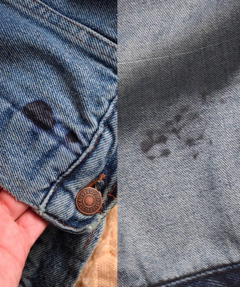 Puede incluir: Primer plano de una chaqueta vaquera azul con un bot&oacute;n de cobre y un logotipo Levi's descolorido. La chaqueta tiene un aspecto desgastado con decoloraci&oacute;n visible y una mancha oscura.
