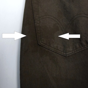 May include: A pair of dark brown jeans with a back pocket. The pocket has a single stitch detail around the opening.