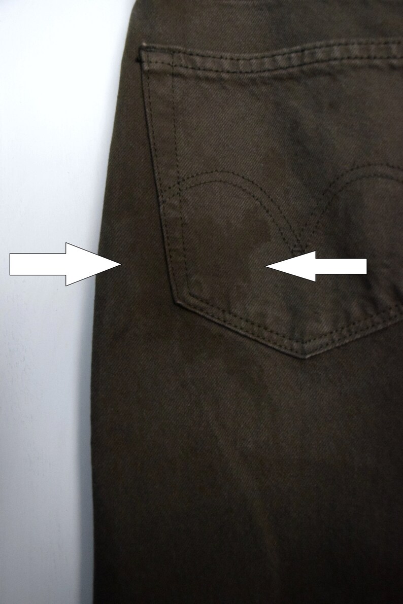 May include: A pair of dark brown jeans with a back pocket. The pocket has a single stitch detail around the opening.