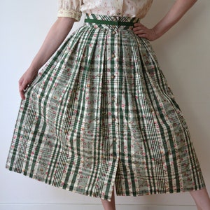May include: A green and white plaid skirt with a floral print. The skirt has a high waist and a button-up front.
