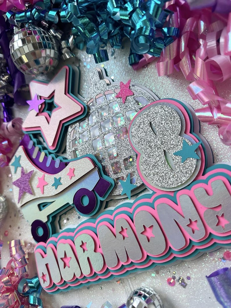 May include: A silver glitter disco ball, a pink and teal roller skate, and a pink, teal, and silver layered name banner that reads "HARMONY". The background is white with silver glitter and pink and teal streamers.