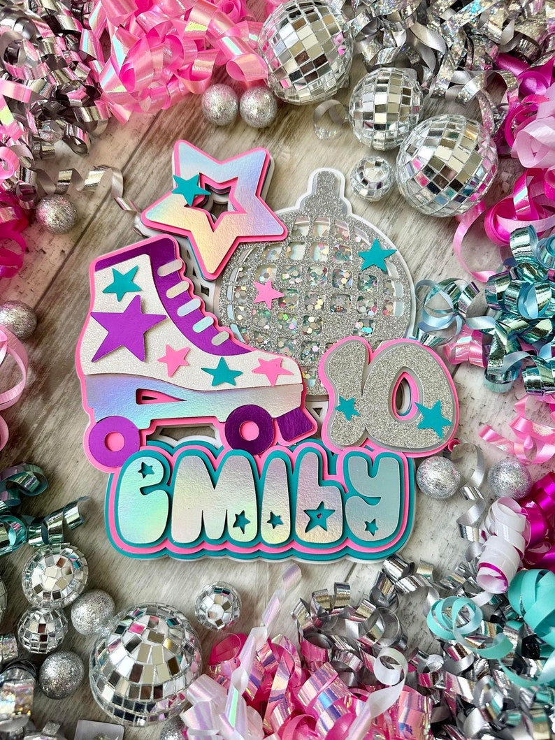 May include: A pink, purple and teal roller skate with a silver disco ball and stars. The name "Emily" is written in a glittery font below the skate. The background is decorated with silver and pink streamers.