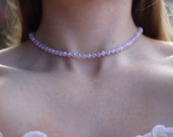 Könnte beinhalten: Eine zarte Choker-Kette aus kleinen, helllila Perlen. Die Kette besteht aus facettierten Glasperlen und ist ein schlichtes, elegantes Schmuckstück.