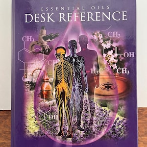May include: A purple book titled "Essential Oils Desk Reference" with illustrations of the human body and chemical structures. The cover features a drop-shaped design with images of a microscope and flowers. The book is compiled by Essential Science Publishing.