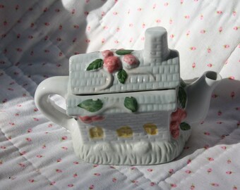 a cute little vintage china teapot in the shape of a house