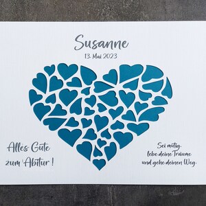 May include: A white card with a teal heart-shaped design filled with smaller hearts. The name "Susanne" and the date "13. Mai 2023" are printed at the top. Text in German is also included.