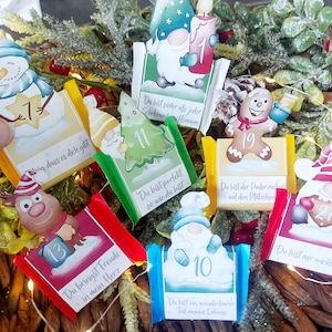 Può includere: Una collezione di biglietti del calendario dell'Avvento a tema natalizio con vari personaggi come un pupazzo di neve, una renna e gnomi. Ogni biglietto ha un numero e una frase in tedesco. I biglietti sono disposti su uno sfondo di verde e luci fatate.