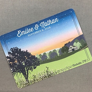 May include: A rectangular card with a scenic landscape illustration. The card features a sunset over a field with a house and trees. The text "Emilee & Nathan September 8, 2018" is displayed at the top, with "Nashville, TN" at the bottom.