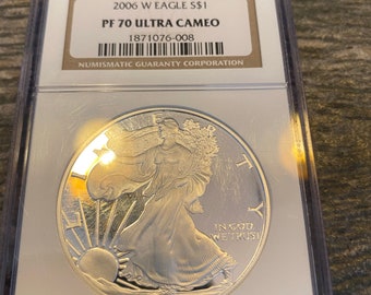 May include: A silver American Eagle coin graded PF 70 Ultra Cameo by the Numismatic Guaranty Corporation. The coin features Lady Liberty walking towards the sunrise with the inscription "In God We Trust" and the year "2006".