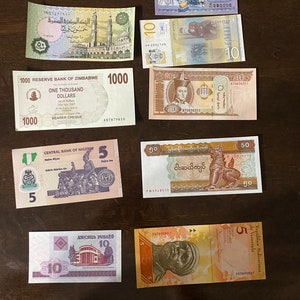 May include: A collection of ten different banknotes from around the world. The banknotes are in various colors and feature different designs, including portraits, buildings, and animals. The banknotes are arranged in a grid pattern on a wooden surface.
