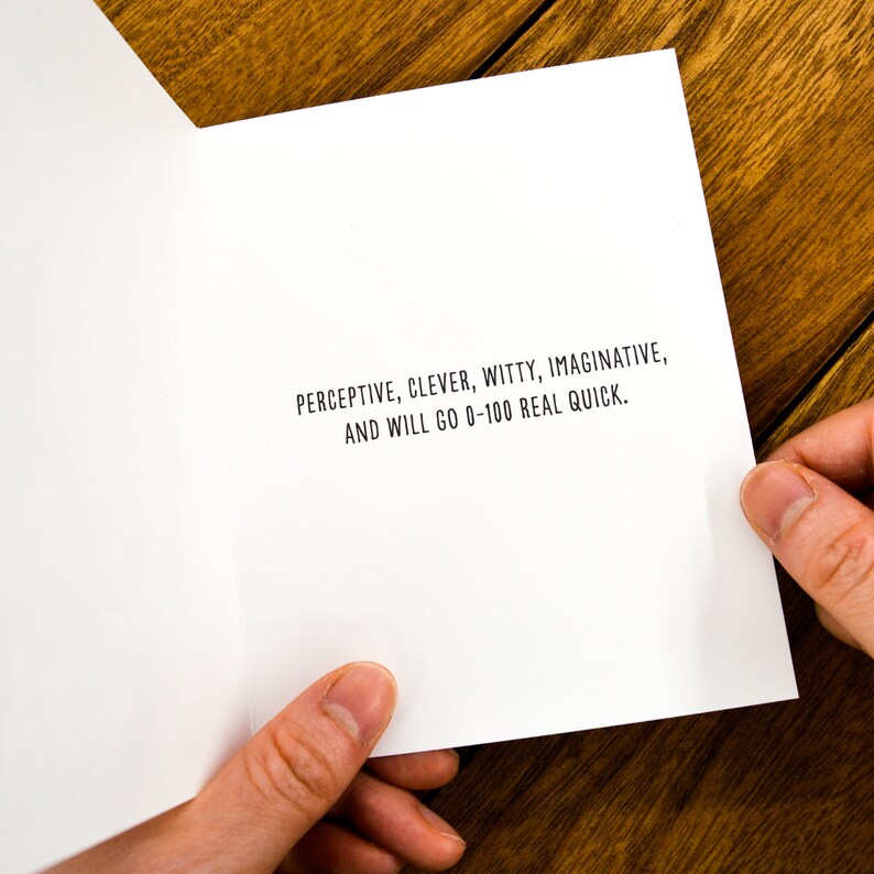 May include: A white card with black text that reads "PERCEPTIVE, CLEVER, WITTY, IMAGINATIVE, AND WILL GO 0-100 REAL QUICK."