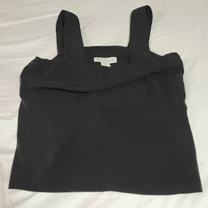 May include: A black sleeveless top with a square neckline and thin straps. The top has a small white label with the text "Dockers" on it.