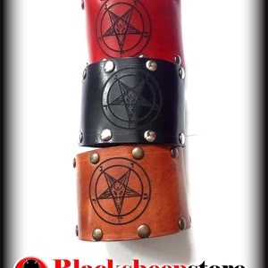Può includere: Tre braccialetti in pelle con un design a pentagramma e borchie metalliche. I braccialetti sono rosso, nero e marrone.