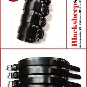 May include: Black leather arm band with multiple buckles and silver studs. The band is made of multiple layers of leather and has a total of four buckles.