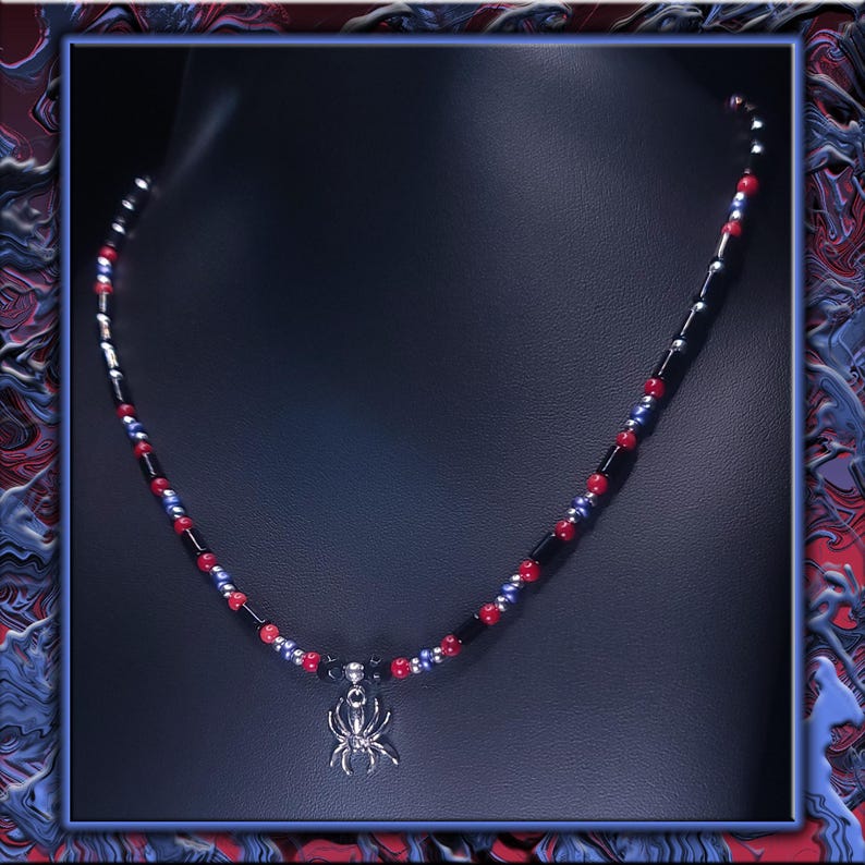 May include: A beaded necklace with a silver spider pendant. The necklace features black, red, and blue beads. The spider pendant is detailed and hangs from the centre of the necklace, displayed on a black background.