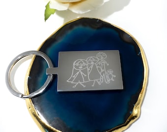 May include: A silver keychain with a rectangular tag featuring a hand-drawn illustration of a family of four. The illustration is engraved on the tag and shows a mother, father, and two children.