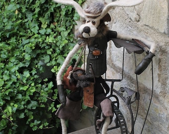 May include: A whimsical, furry, white rabbit doll with a brown leather jacket and a brown hat, riding a metal bicycle with a single wheel. The doll has a brown leather bag and a small, furry, brown animal doll hanging from its shoulder.