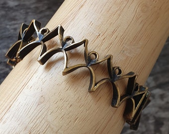 May include: A gold-toned metal bracelet with a geometric design. The bracelet is made up of multiple interlocking pieces that form a repeating pattern.