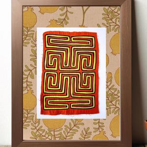 May include: A framed artwork featuring a red and yellow geometric pattern with black outlines. The pattern is a series of interlocking squares and rectangles, creating a maze-like design.