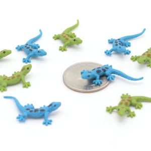 May include: A collection of ten small plastic toy lizards. Five of the lizards are green with brown spots and five are blue with black spots.