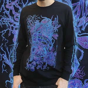 Op de afbeelding: Zwart shirt met lange mouwen met een gedetailleerde, surrealistische afbeelding in blauw- en paarstinten. Het ontwerp toont een complexe opstelling van organische vormen, ogen en tentakels. De mouwen hebben ook een blauw-paars ontwerp.
