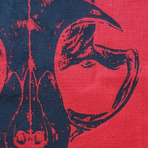 May include: A black and white skull design printed on a red fabric background.