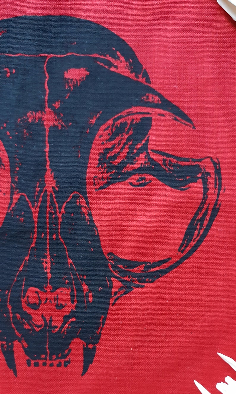 May include: A black and white skull design printed on a red fabric background.