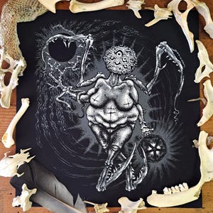 May include: A black fabric square featuring a white stippled illustration of a multi-eyed, multi-limbed creature with sharp, claw-like appendages. The figure holds a glowing geometric lantern against a dark, swirling background of radiating lines.