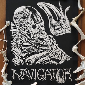 May include: Black and white patch featuring a detailed illustration of a creature with a skull-like head and the word "NAVIGATOR" in a gothic font.