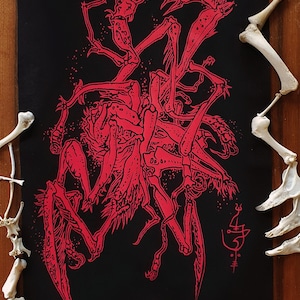 Op de afbeelding: Rode inkt-illustratie van een skeletachtig wezen met meerdere ledematen en een spinachtig uiterlijk op een zwarte stoffen achtergrond.