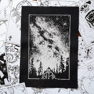 May include: Black and white patch featuring a starry night sky over a forest, with the words "The Star" at the bottom. The patch is surrounded by other tarot card designs.