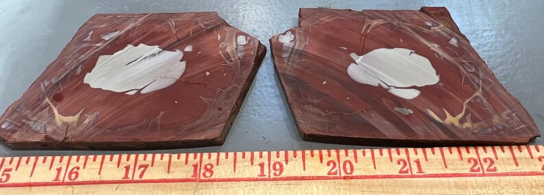 May include: Two reddish-brown, irregularly shaped stone slabs with a white, cloud-like pattern in the center. The slabs are placed side by side, with a wooden ruler below, showing measurements from 15 to 22 inches.
