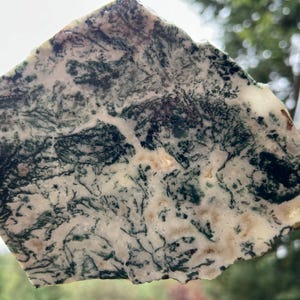 May include: A natural stone slab with a unique pattern of green, white, and tan colors. The stone has a rough, irregular shape and a polished surface. The intricate veining creates a natural, artistic design. This decorative stone is ideal for home decor.