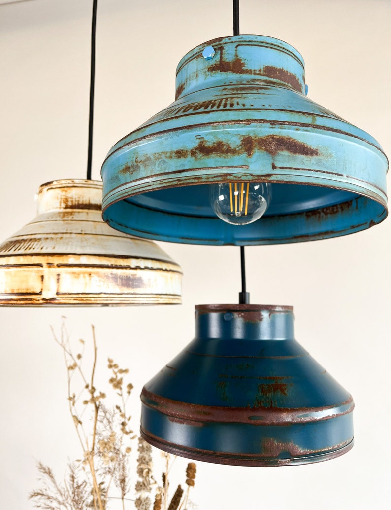 May include: Three pendant lights with distressed metal shades in blue, teal, and white. The shades have a rustic, vintage look with visible rust and wear.