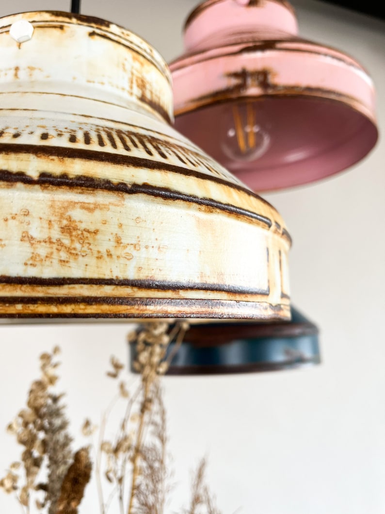 May include: Three vintage-style pendant lights with a rustic, distressed finish. The lights are in shades of white, pink, and blue.