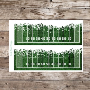 May include: Two rectangular prints of a football field, featuring green grass, white yard lines, and numbers. The field has a textured appearance, with the yard lines and numbers clearly visible. The text "10 20 30 40 50 40 30 20 10" is repeated.