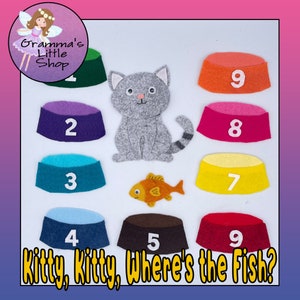 May include: A felt educational game featuring a gray cat, a gold fish, and nine colorful bowls numbered 1-9. The text "Kitty, Kitty, Where's the Fish?" is at the bottom. The shop logo is in the upper left corner.