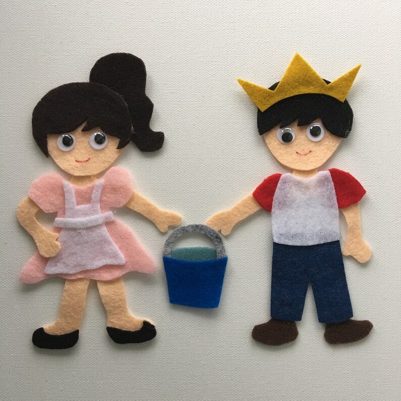 May include: Felt figures of a girl in a pink dress and a boy wearing a gold crown, red-sleeved shirt, and blue jeans. They are holding a blue bucket with a gray handle. The figures have googly eyes and are smiling.