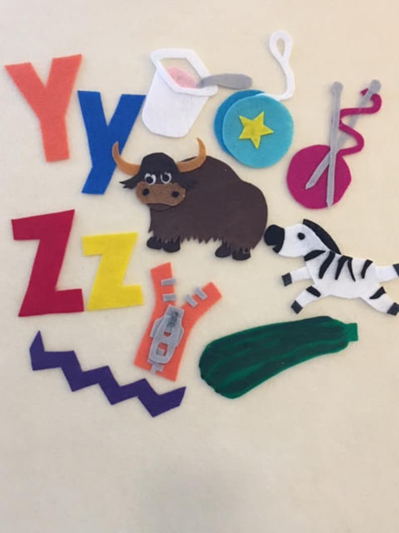 May include: Felt craft letters Y, Z, and Y, a brown yak, a green zucchini, a white yogurt container, a blue yo-yo, a pink yarn ball with two knitting needles, a purple zigzag, and a gray zipper.