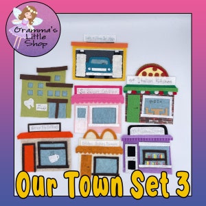 May include: Felt play set of eight different shops for pretend play. The shops include a car wash, a candy store, a pizza kitchen, a coffee shop, a burger restaurant, a bookstore, a dentist's office, and a building with no specific shop name. The set is titled "Our Town Set 3".
