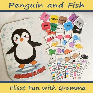 May include: A penguin and fish matching game for kids. The game includes a penguin-shaped box with a flap that says "Penguin & Fish". There are color and number cards with fish and a penguin. The cards are color-coded with the words "pink", "yellow", "brown", "purple", "grey", "red", "green", "white", "blue", "black", and "orange".