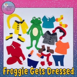 May include: A green felt frog figure surrounded by various felt clothing items including a yellow raincoat, red pajamas, a teal shirt, a grey jacket, an orange shirt, blue shorts, brown boots, yellow boots, orange socks, a red scarf, and a red hat.