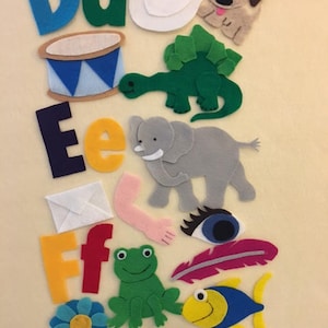 May include: Felt letter set for children, featuring the letters D, E, and F, with corresponding images for each letter. The images include a duck, dog, drum, dinosaur, elephant, envelope, frog, feather, fish, and flower.