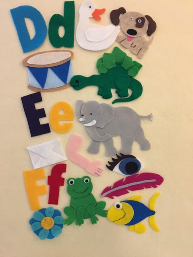 May include: Felt letter set for children, featuring the letters D, E, and F, with corresponding images for each letter. The images include a duck, dog, drum, dinosaur, elephant, envelope, frog, feather, fish, and flower.