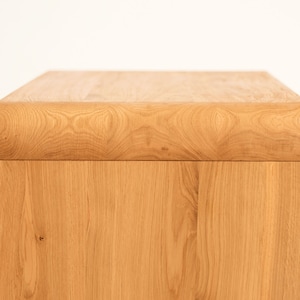 May include: A light wood side table with a rounded top edge. The table is made of solid wood and has a natural finish.