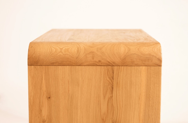 May include: A light wood side table with a rounded top edge. The table is made of solid wood and has a natural finish.