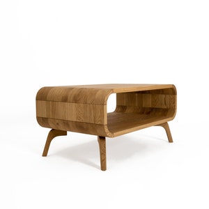 May include: A wooden coffee table with a curved, open design and four legs. The table is made of light brown wood and has a natural finish.