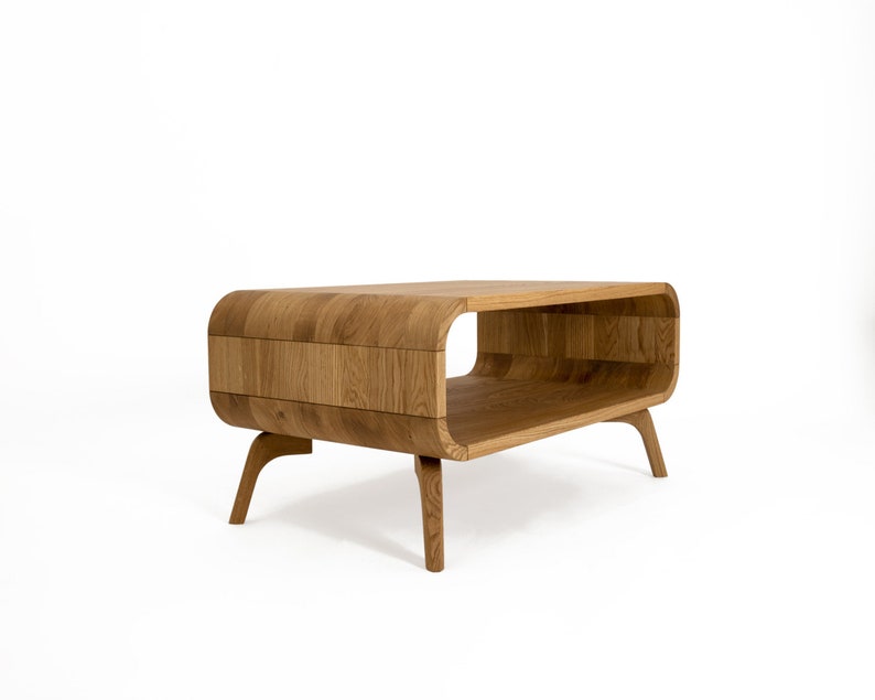 May include: A wooden coffee table with a curved, open design and four legs. The table is made of light brown wood and has a natural finish.
