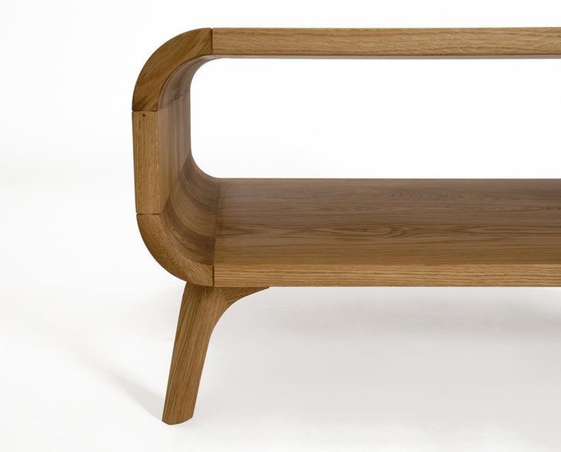 May include: A wooden coffee table with a curved design and a lower shelf. The table has a natural wood finish and four legs.